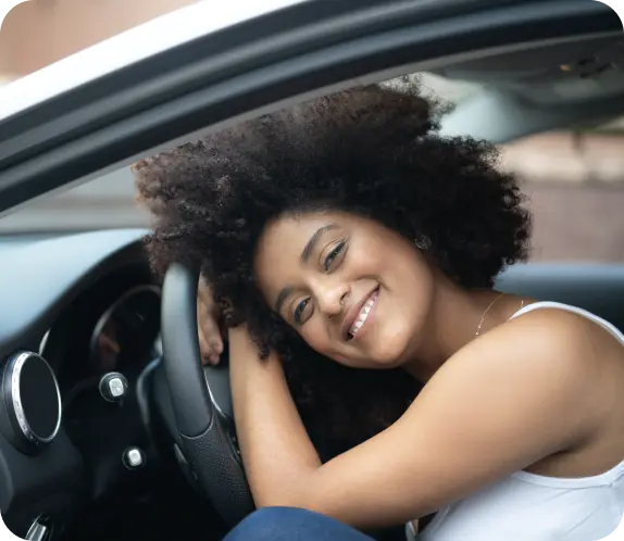 Mulher sorrindo encostada na direção do carro