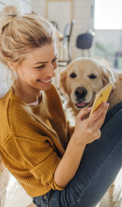 Mulher segurando o celular, com seu cachorro ao lado